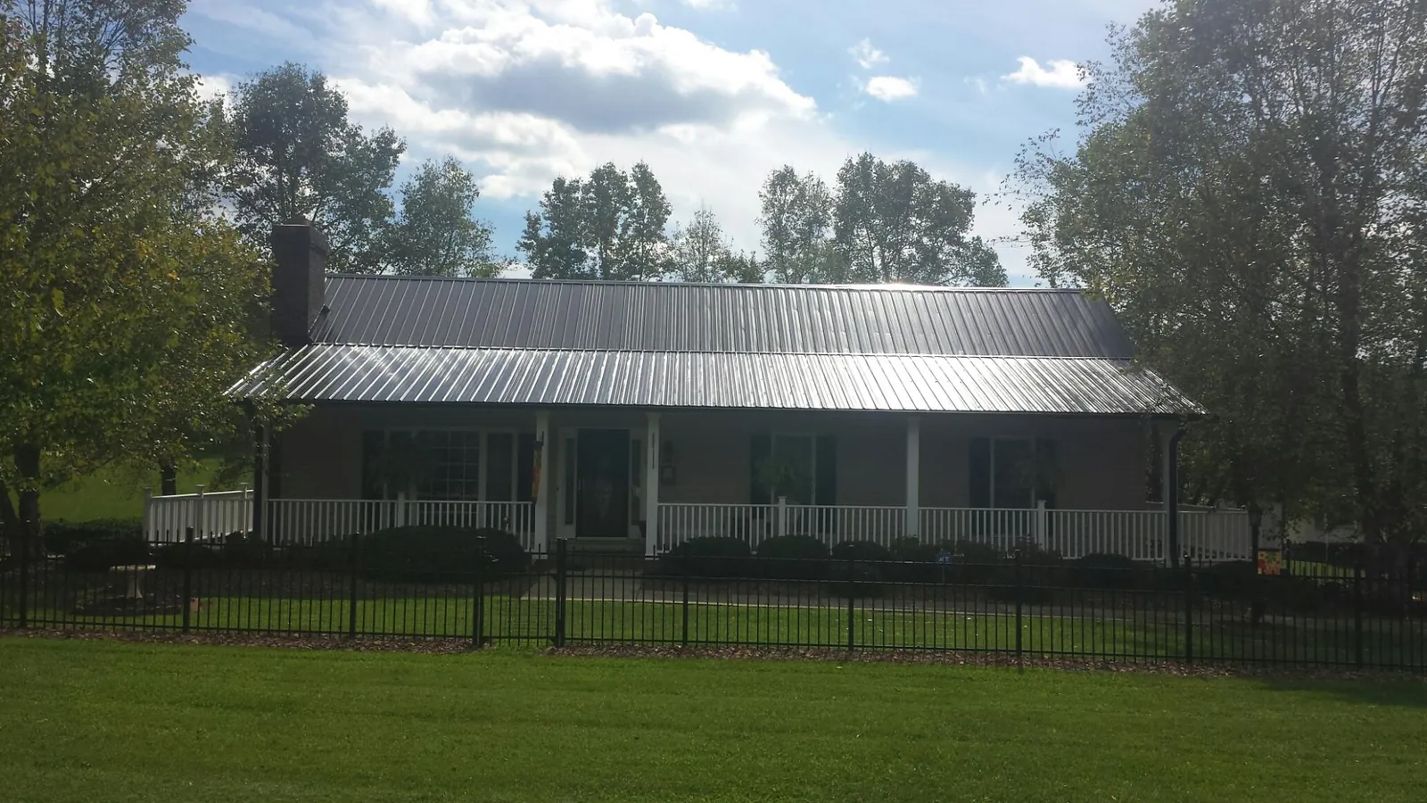 Gray metal roof on a brick ranch with a full width front porch — Gutter Guard Installation work by our crew in Williamstown